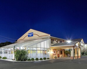 A Rodeway Inn with a large glass facade, a covered outdoor area, and a well-lit entrance.