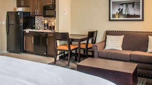 A compact hotel room with a kitchenette, a dining area, a sofa, and a bed. - MainStay Suites Cotulla (Cotulla)