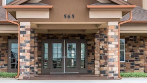 A building entrance with a stone facade, double doors, and the number 565 above. - MainStay Suites Cotulla (Cotulla)