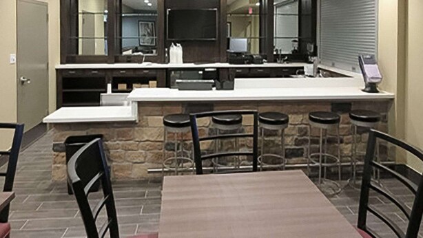 A modern kitchen with a central island, bar stools, and a dining table. - MainStay Suites Cotulla (Cotulla)