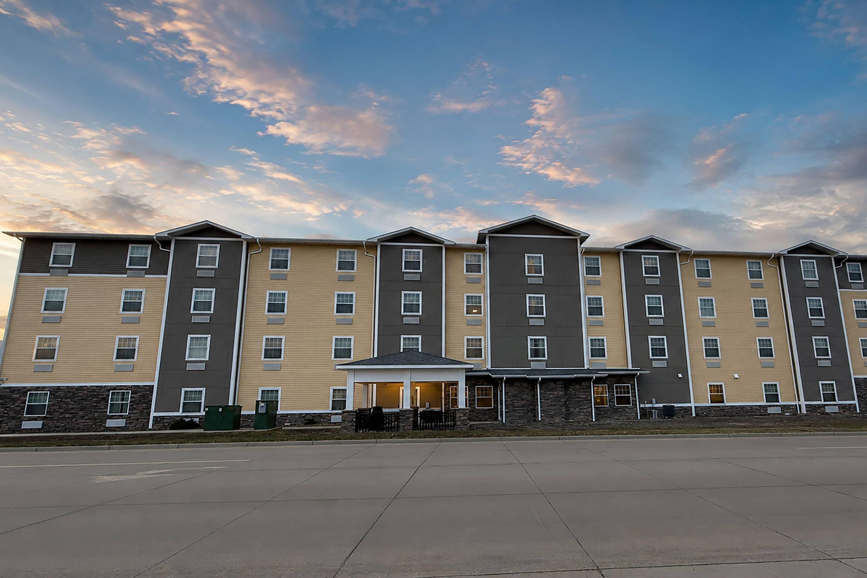 A multi-story hotel with a flat facade, a covered entrance, and a parking lot.