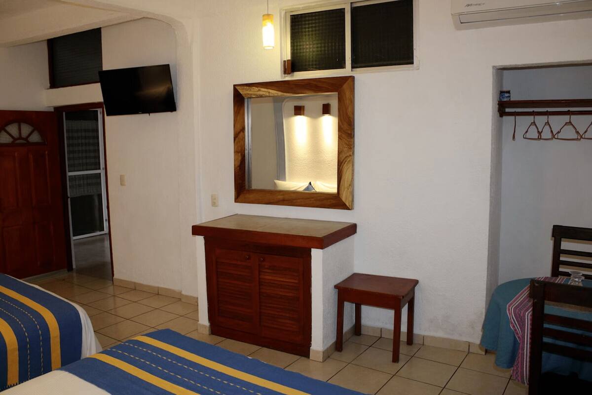 Une pièce comprenant une commode en bois, une petite table, un miroir, un téléviseur et une armoire.
