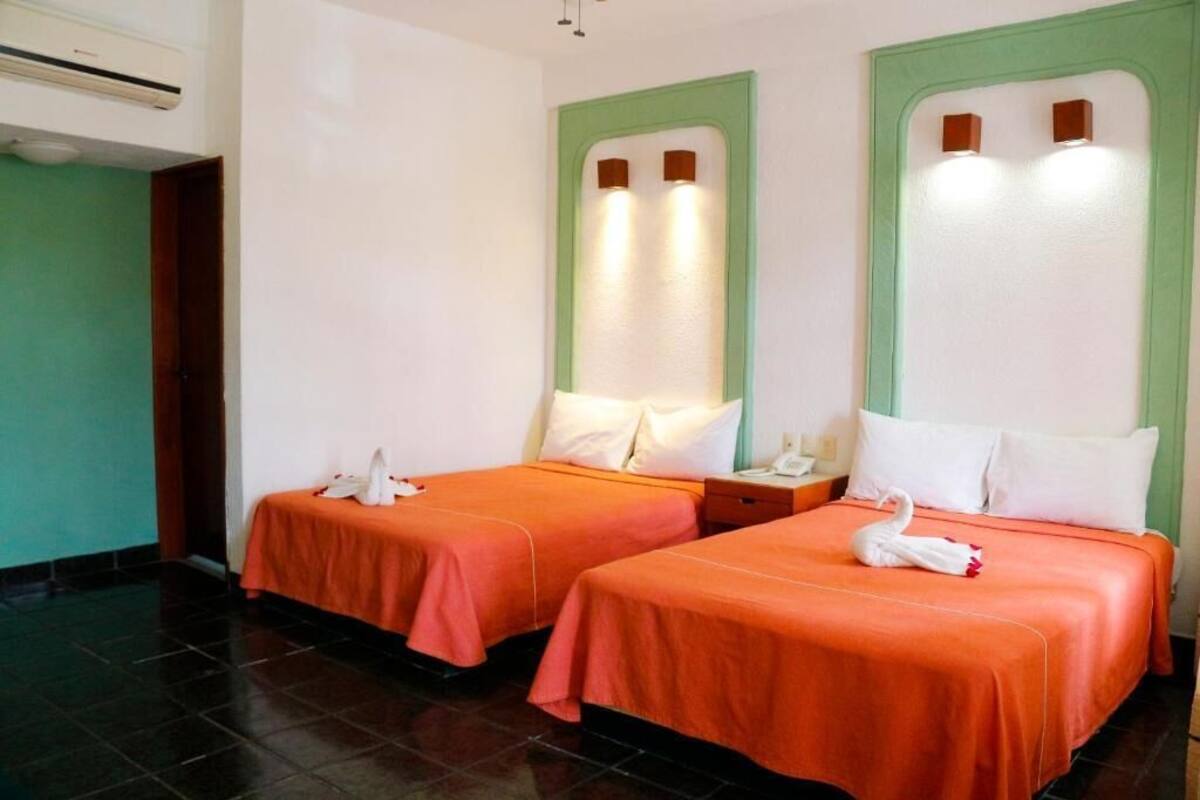 Deux lits simples avec une literie orange, des oreillers blancs et une décoration en forme de cygne.