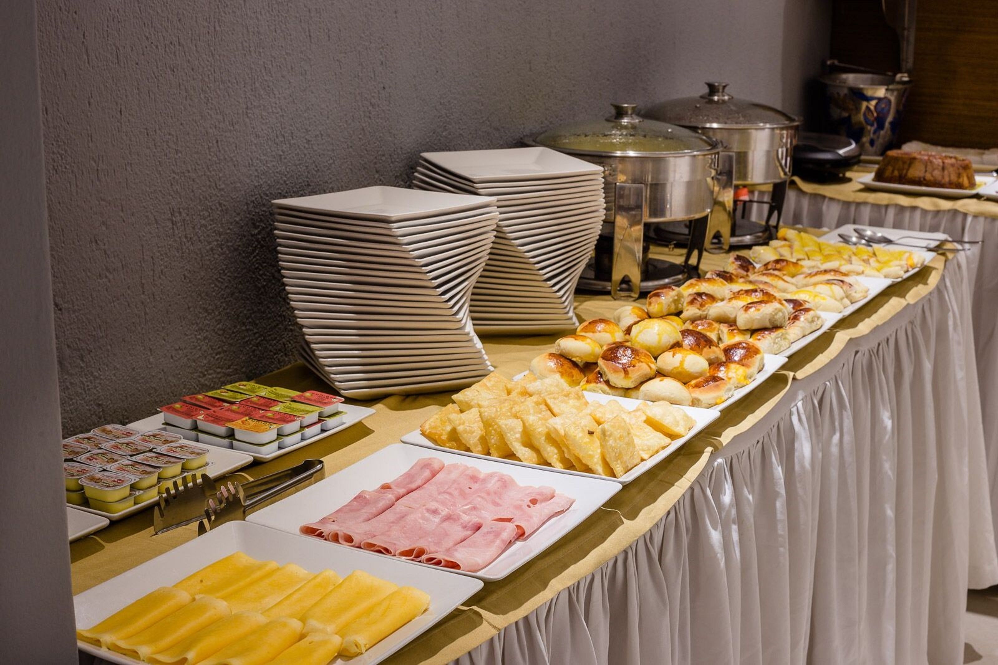 A buffet table with various food items, including pastries, meats, and fruits.