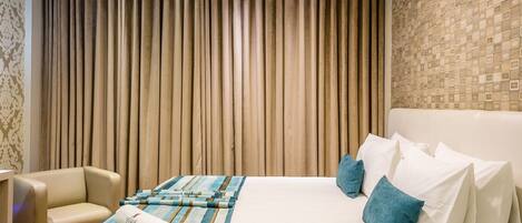 A hotel room with a large bed, a sofa, and a curtain backdrop.