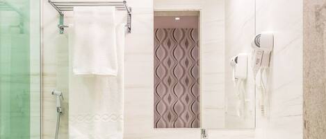 A modern bathroom with a glass shower enclosure, a white toilet, a vanity with a mirror, and a towel rack.