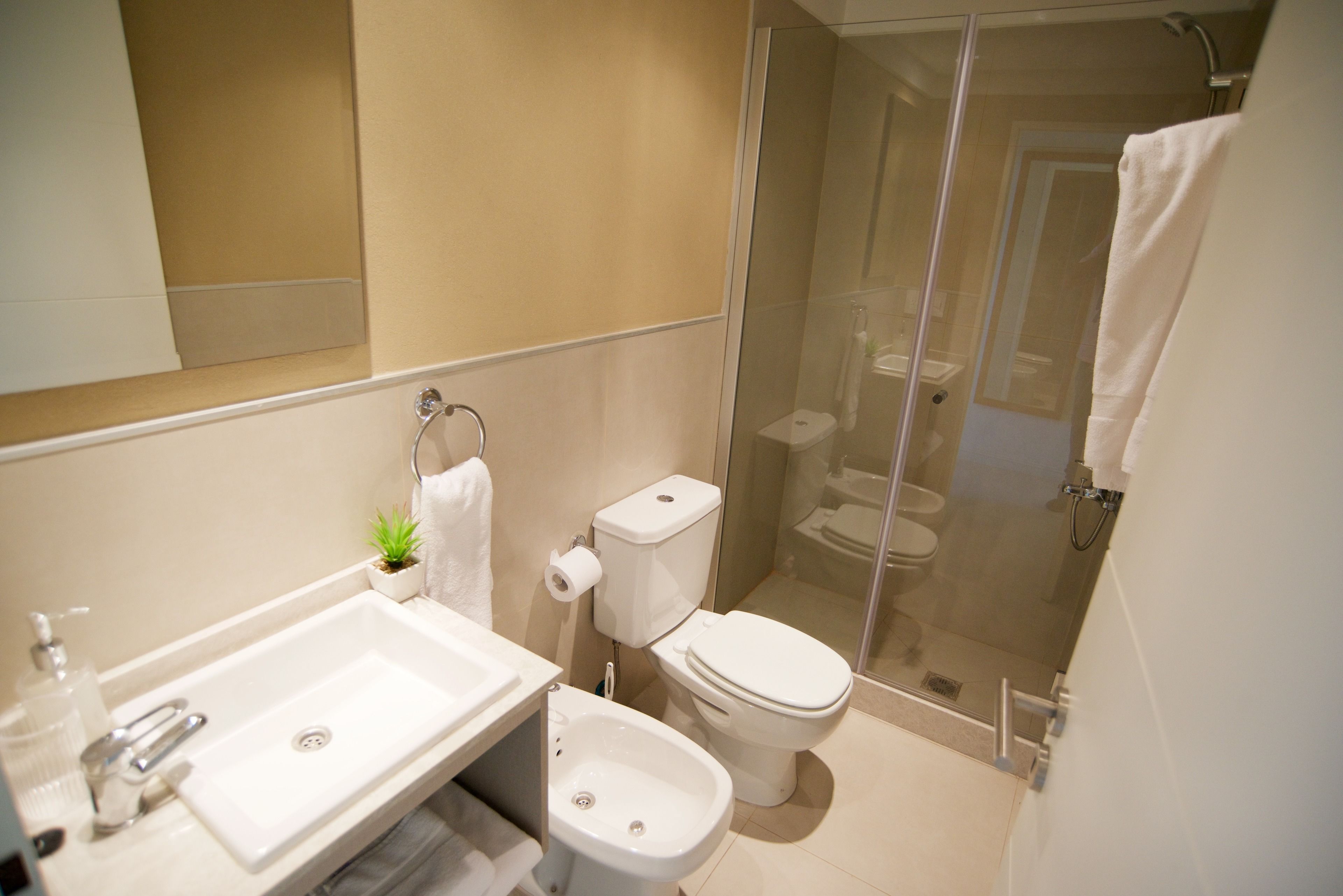Un bagno moderno con lavandino, water, bidet e doccia vetrata.