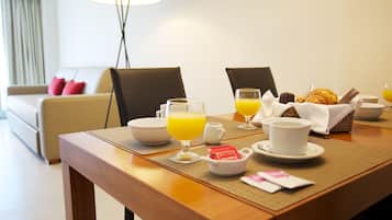 A breakfast table with croissants, orange juice, and coffee cups.