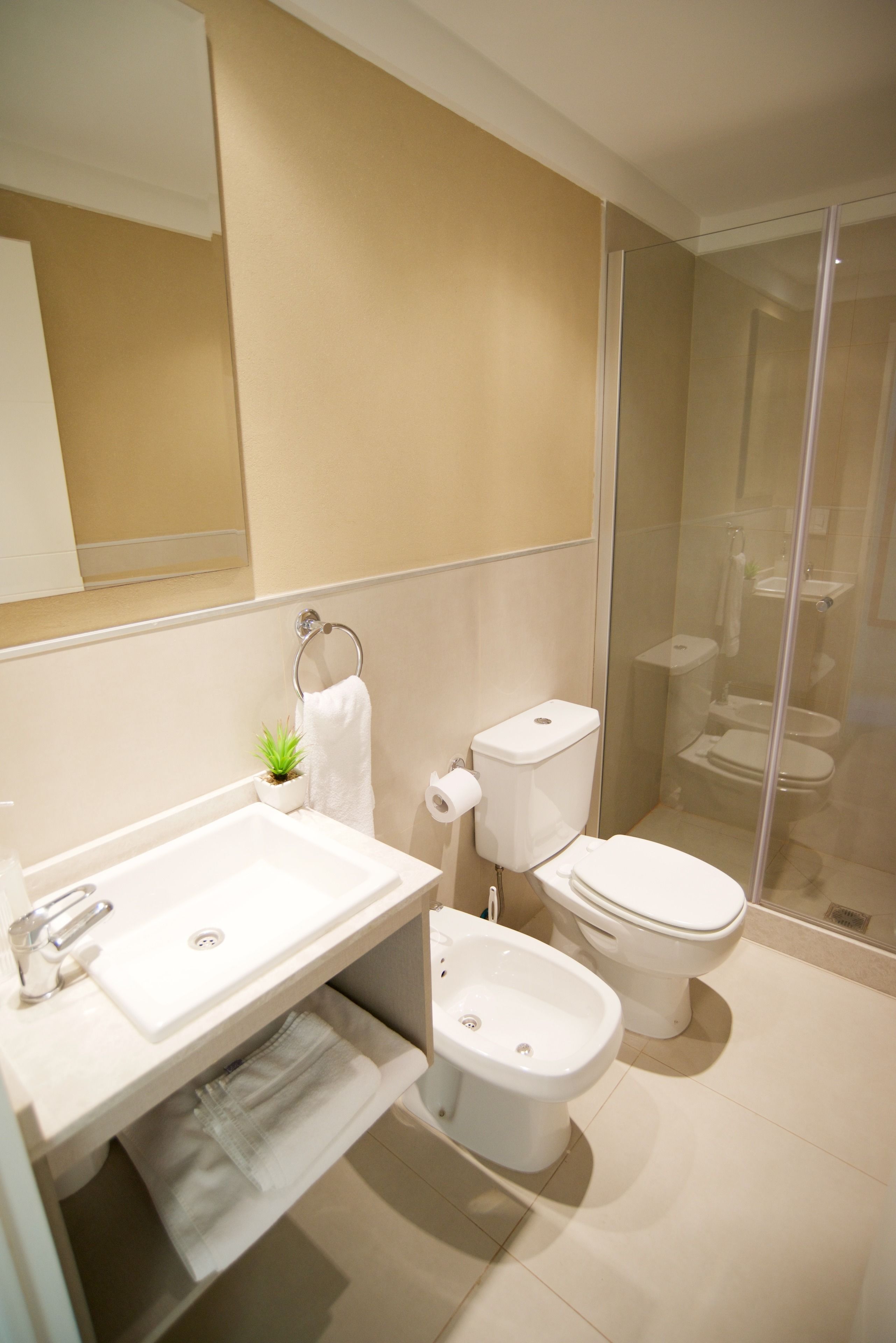 Een moderne badkamer met een wastafel, toilet, douchecabine en een bidet.