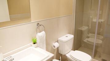 Een moderne badkamer met een wastafel, toilet, douchecabine en een bidet.