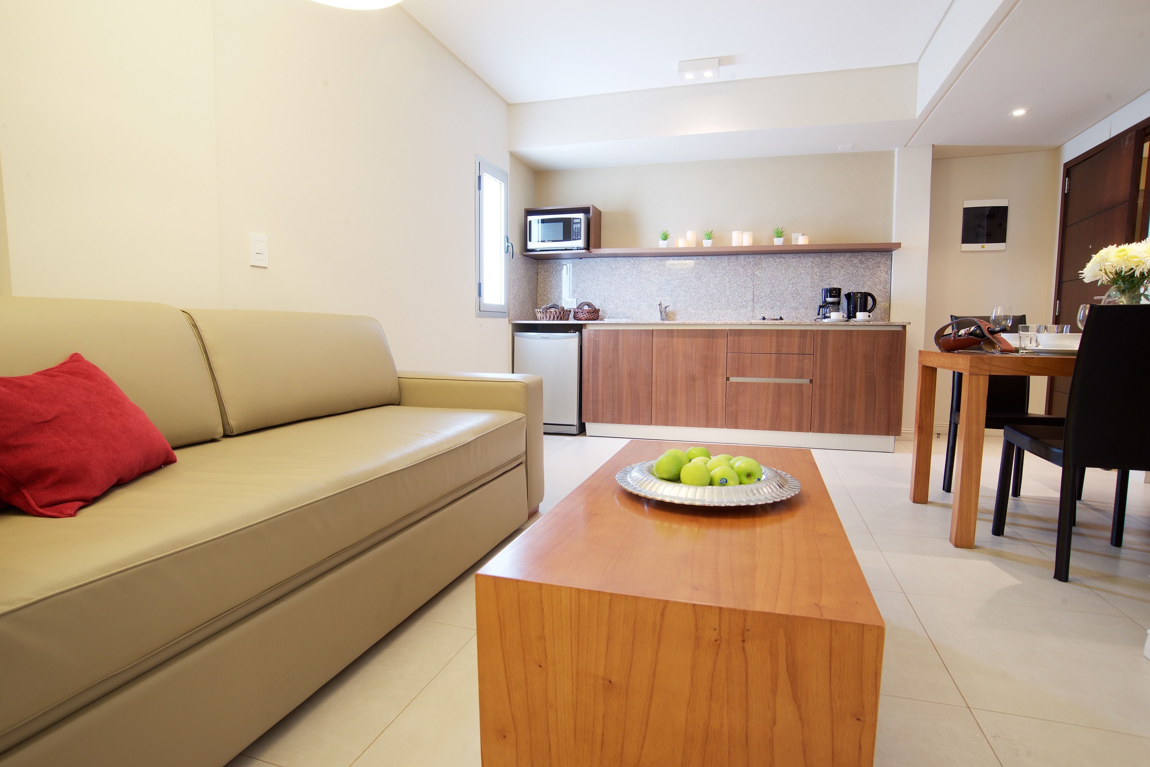 Una cocina moderna con microondas, cafetera y comedor con mesa y sillas.