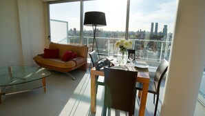 Una sala de estar moderna con una mesa de vidrio, un sofá y una zona de comedor con sillas y una lámpara.