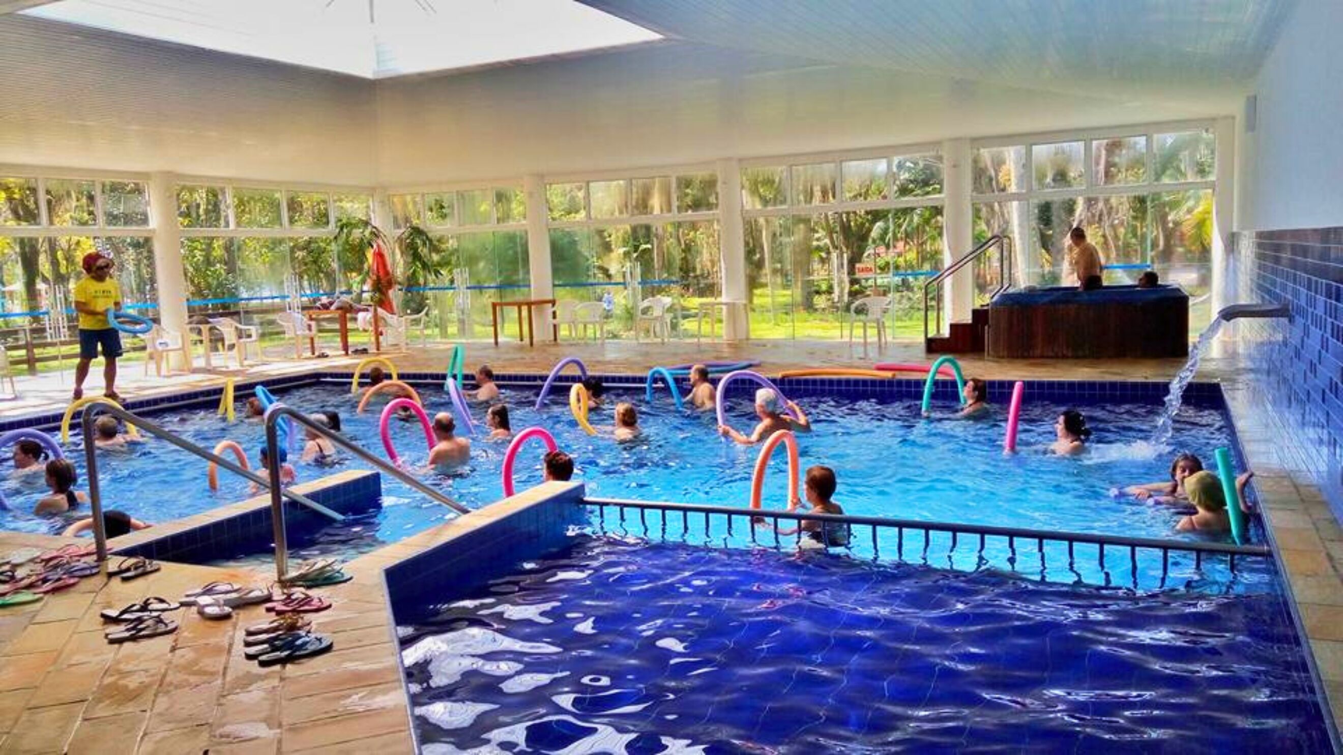 An indoor swimming pool with multiple lanes, clear water, and safety railings.