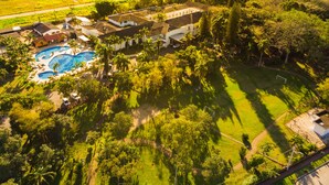 An aerial view of a resort with a swimming pool, palm trees, and a large building. - Hotel Termas do Gravatal (Gravatal)