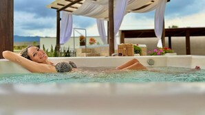 A person relaxing in a hot tub with a pergola and flowers in the background. - Hotel Termas do Gravatal (Gravatal)