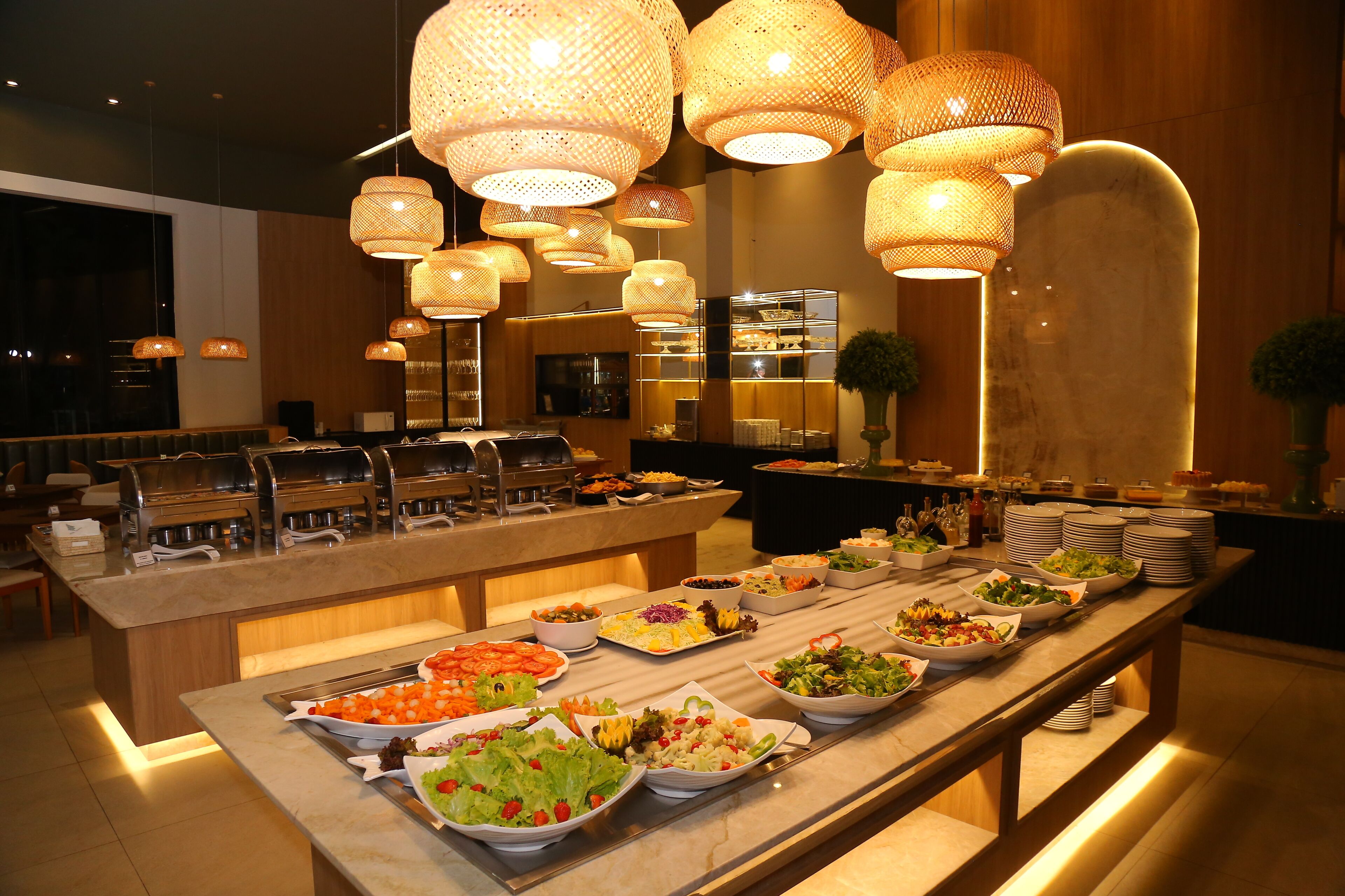 Buffet com diversas opções de comida e área de estar com um banco de madeira.