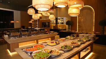 Buffet com diversas opções de comida e área de estar com um banco de madeira.