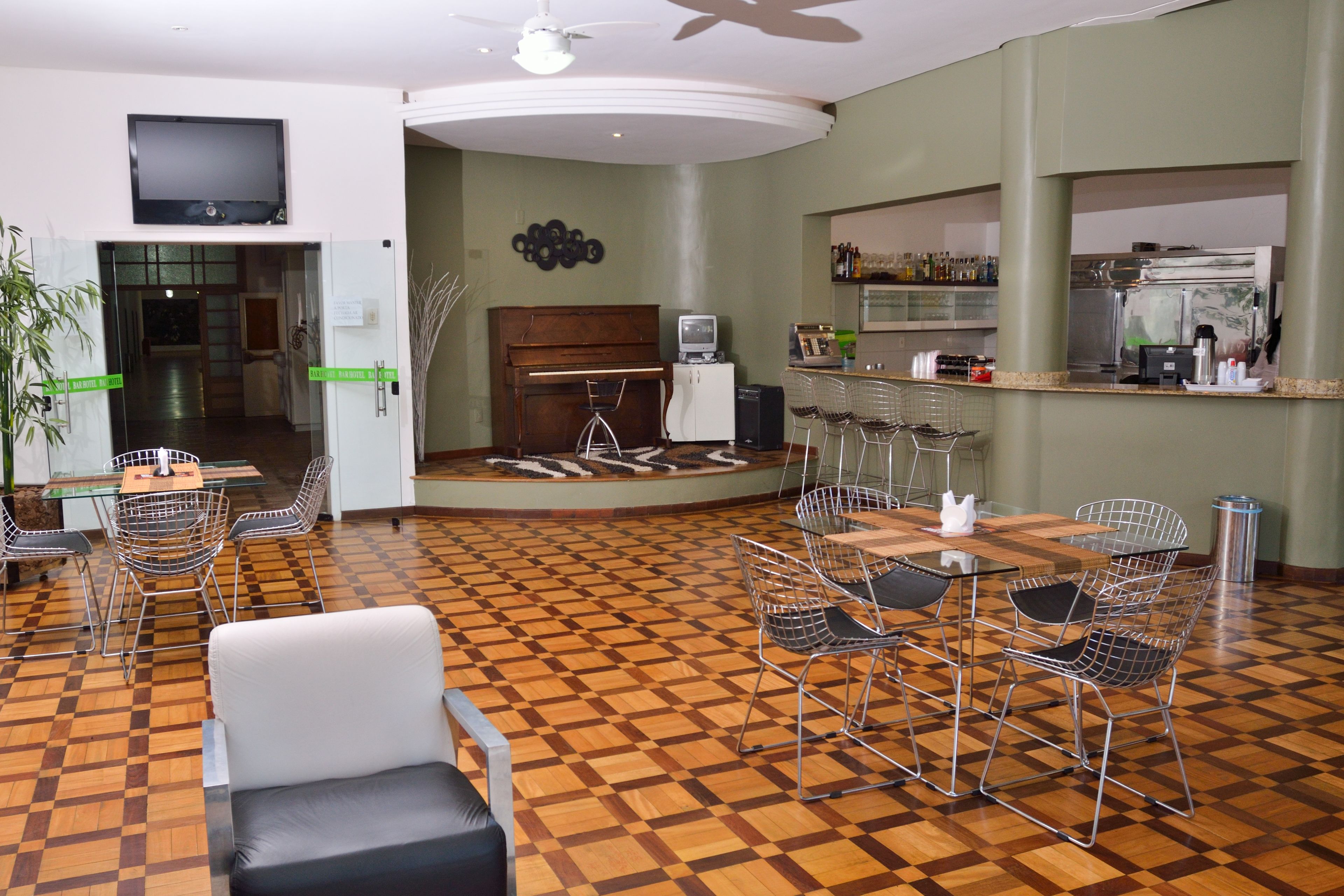 Um saguão de hotel com piso xadrez, um piano, área de bar e disposição de assentos.
