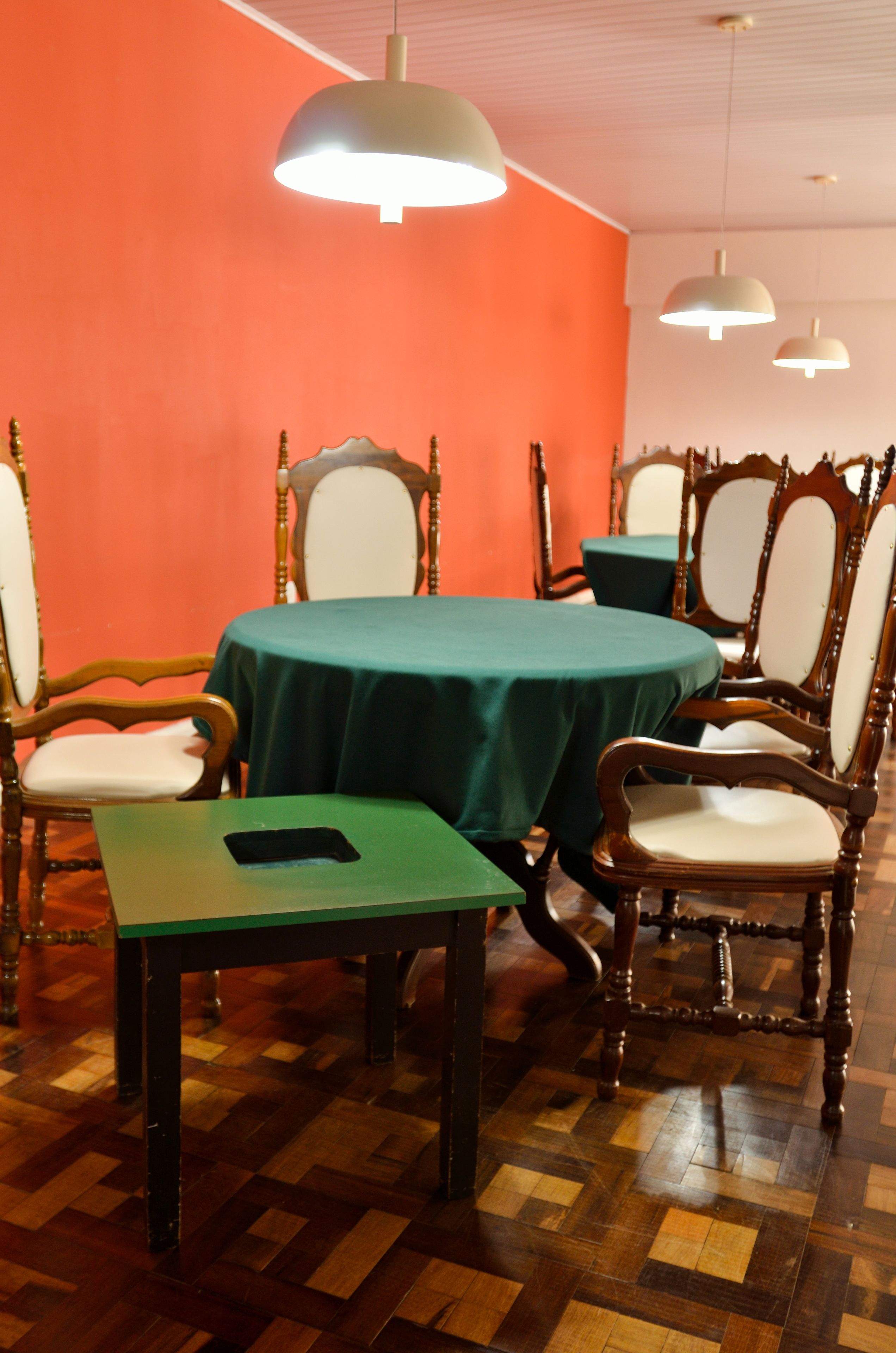 Un comedor con una mesa redonda, sillas y lámparas colgantes.