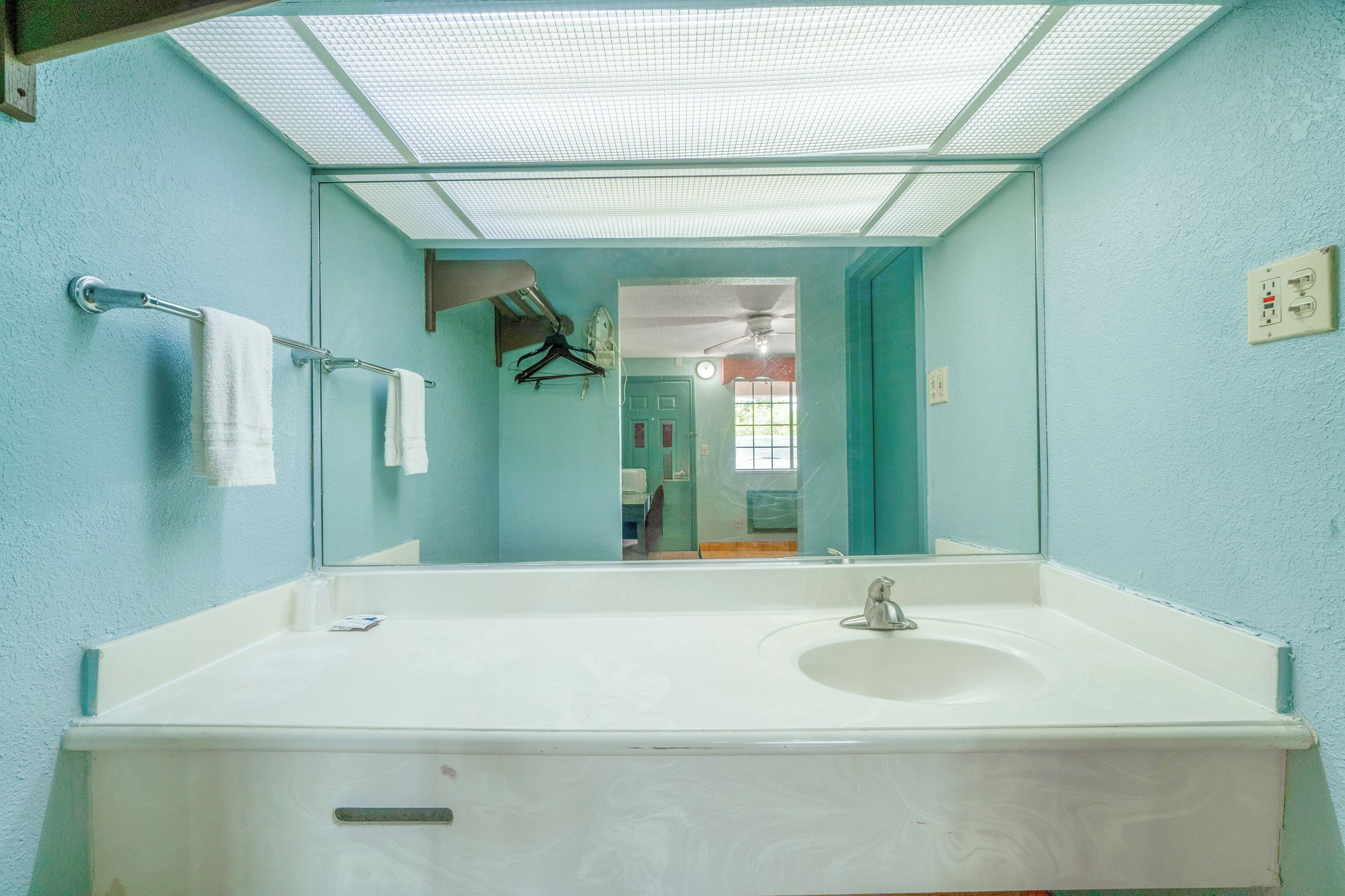 A bathroom with a large mirror, a white sink, and a towel rack.