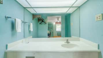 A bathroom with a large mirror, a white sink, and a towel rack.