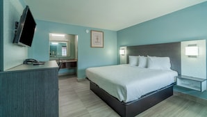 A modern hotel room with a large bed, a desk with a telephone, a flat-screen TV mounted on the wall, and a framed picture above the bed.