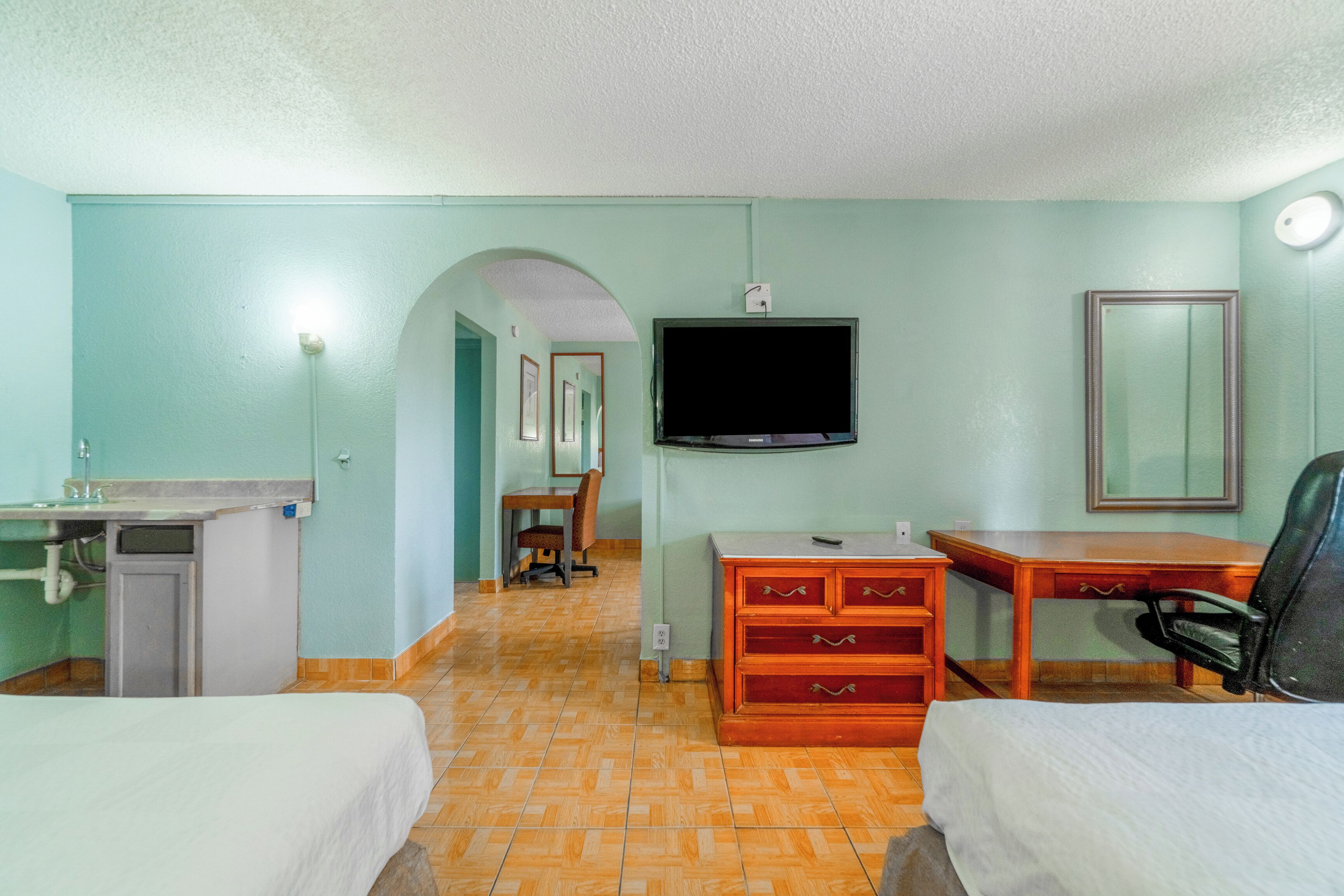 Una habitación de hotel con dos camas, un escritorio, una silla, un televisor y un aparador.
