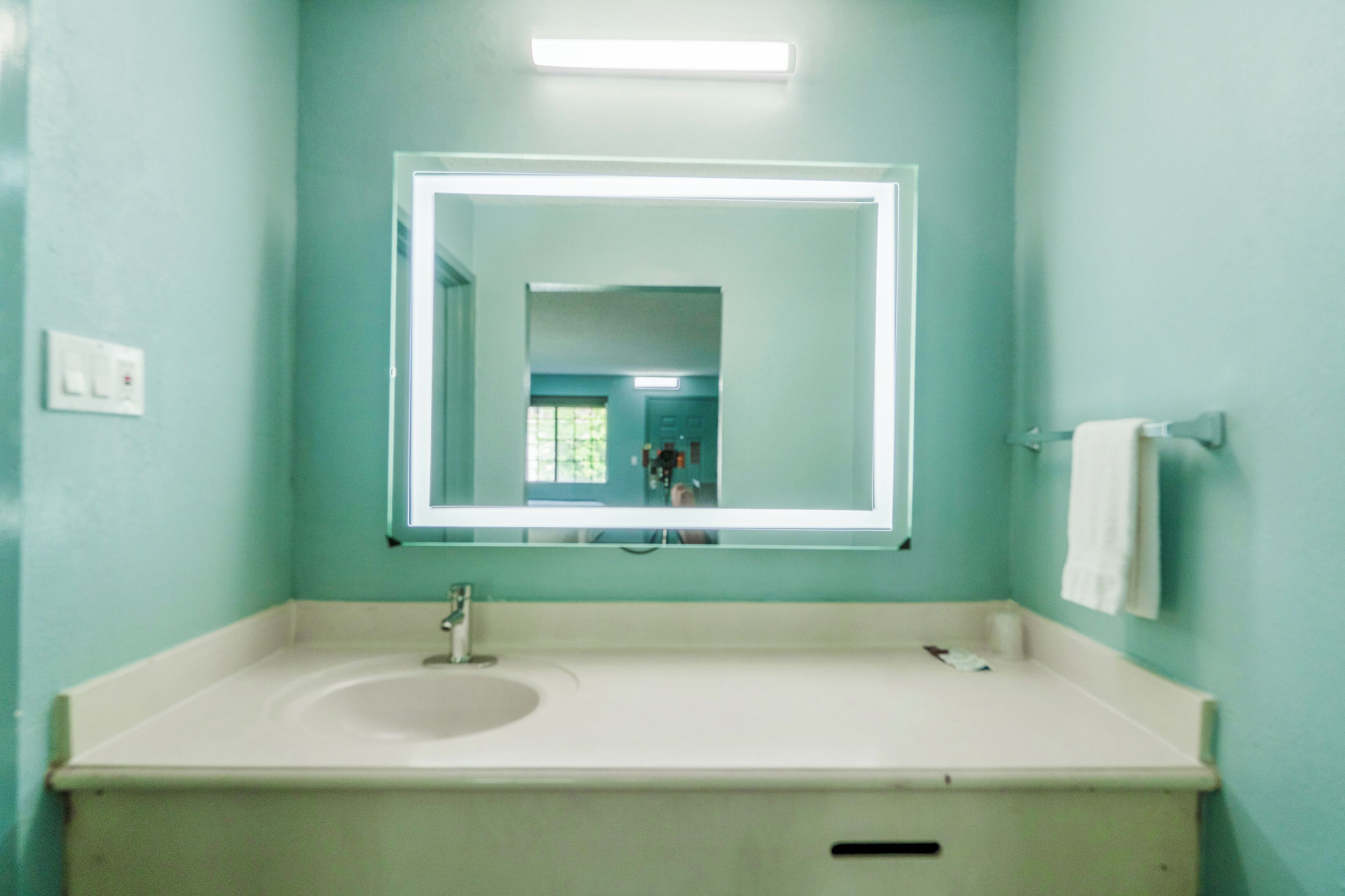 A bathroom with a white sink, a mirror, and a towel rack.