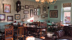 Comedor con muebles de madera, una araña y cuadros en las paredes.