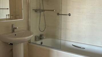 A bathroom with a sink, mirror, shower, and bathtub.
