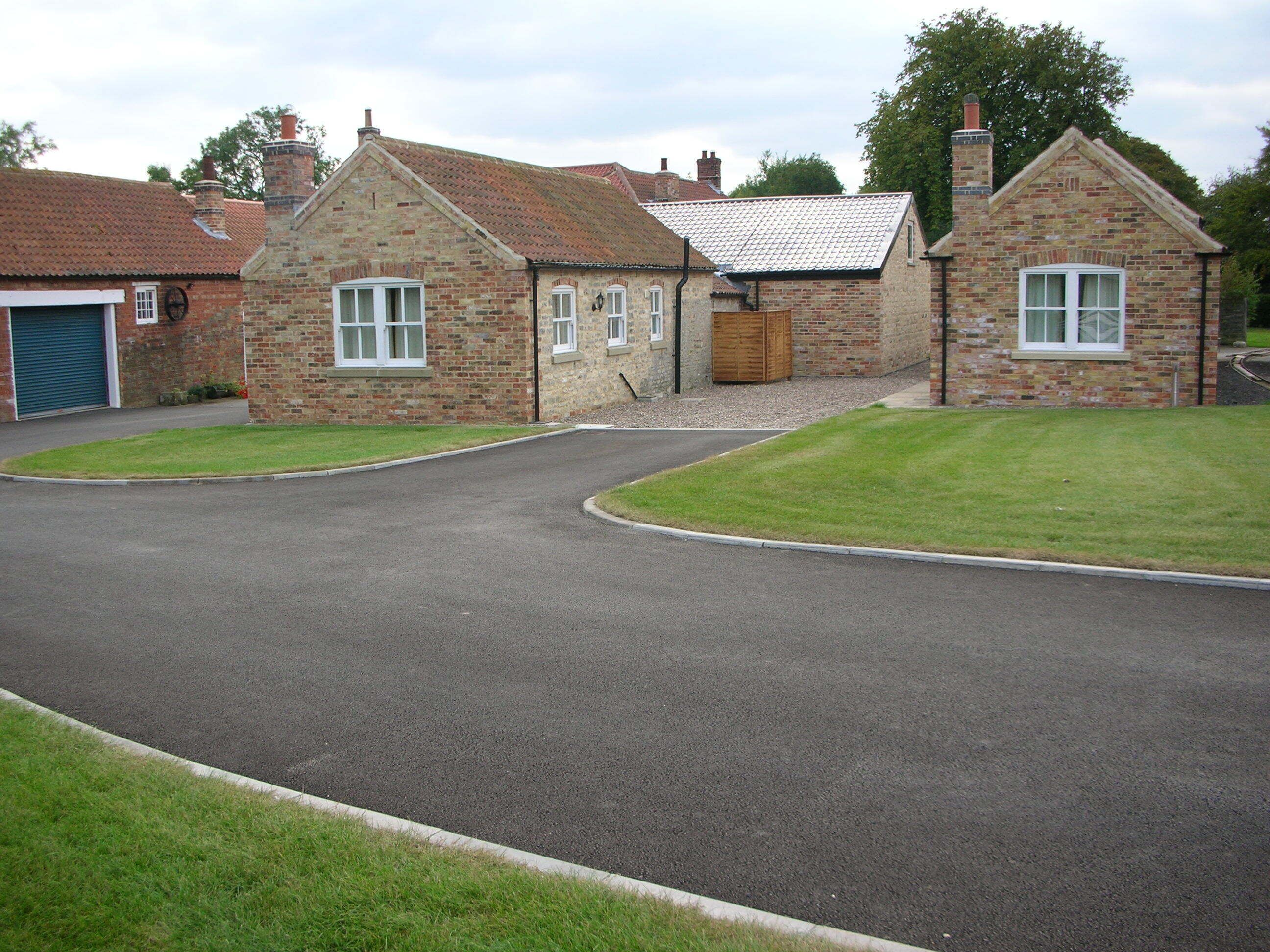 A two-story brick house with a curved driveway leading to a garage.
