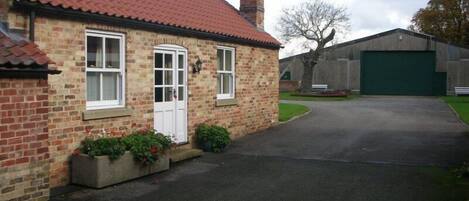 A brick house with a red-tiled roof, a chimney, and a garage.
