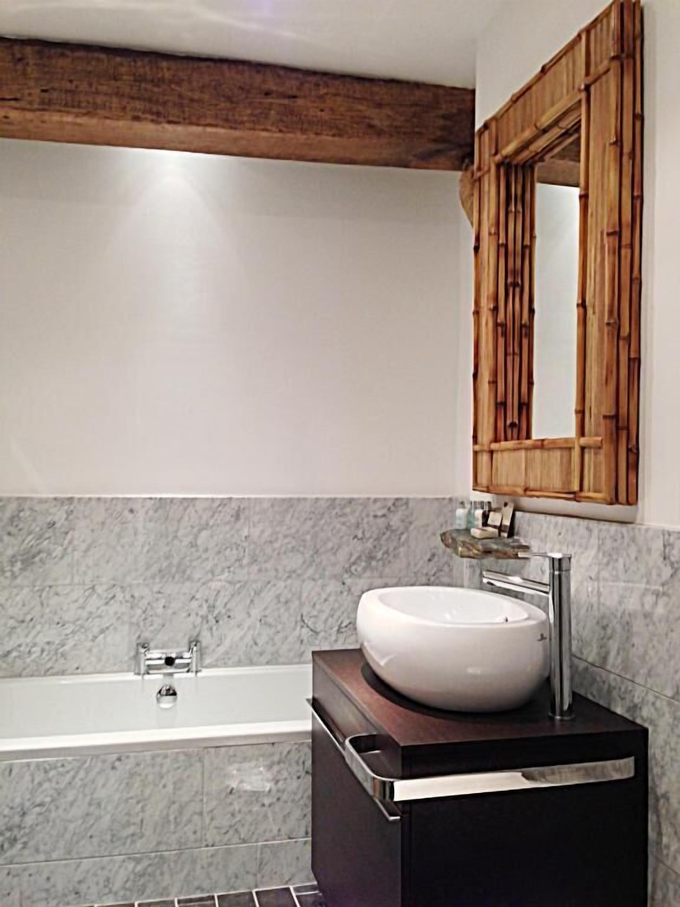 A bathroom with a bathtub, a white sink, and a wooden-framed mirror.