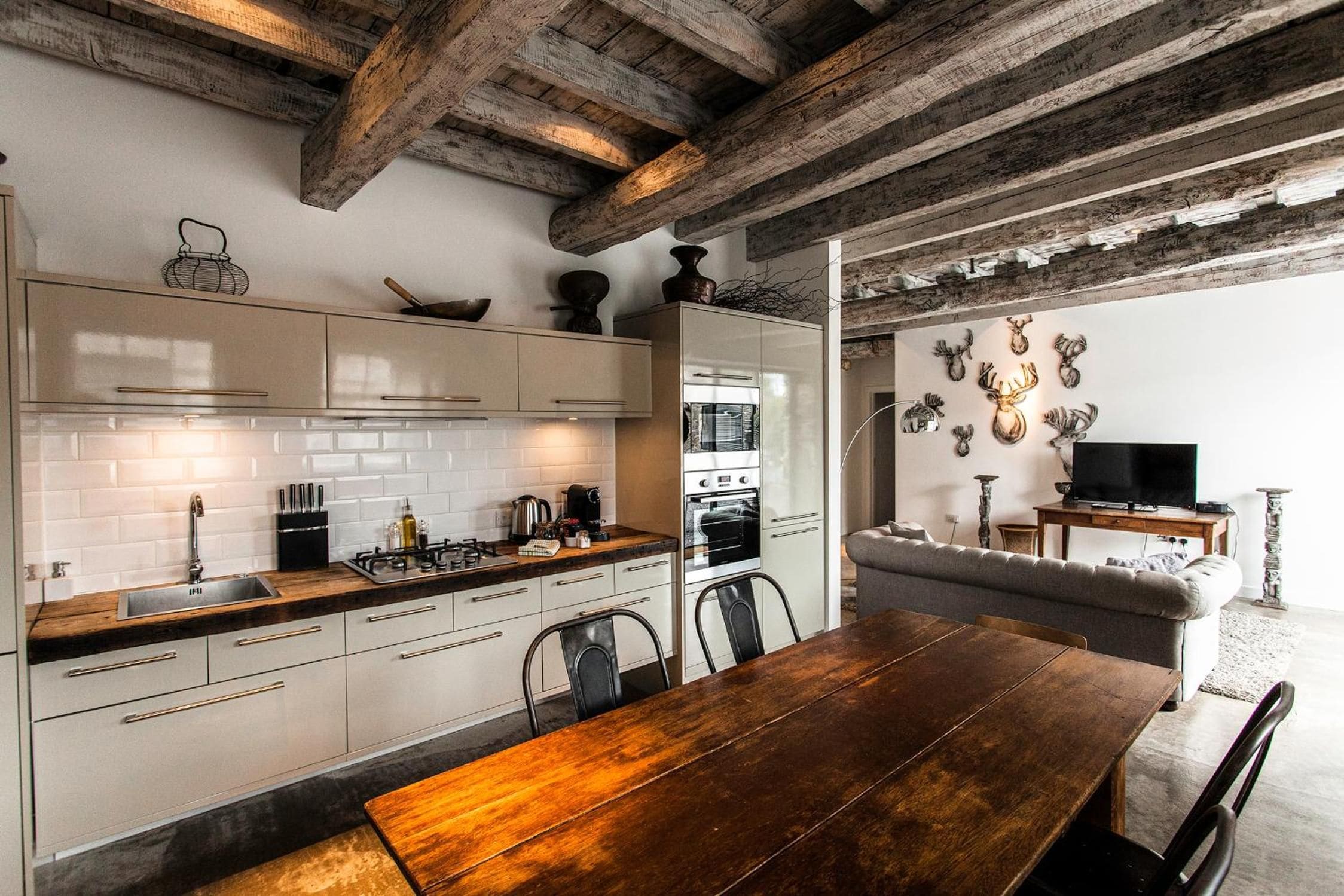 Una cocina con armarios blancos, una mesa de comedor de madera y una chimenea de piedra.