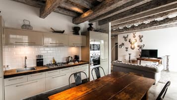 Una cocina con armarios blancos, una mesa de comedor de madera y una chimenea de piedra.