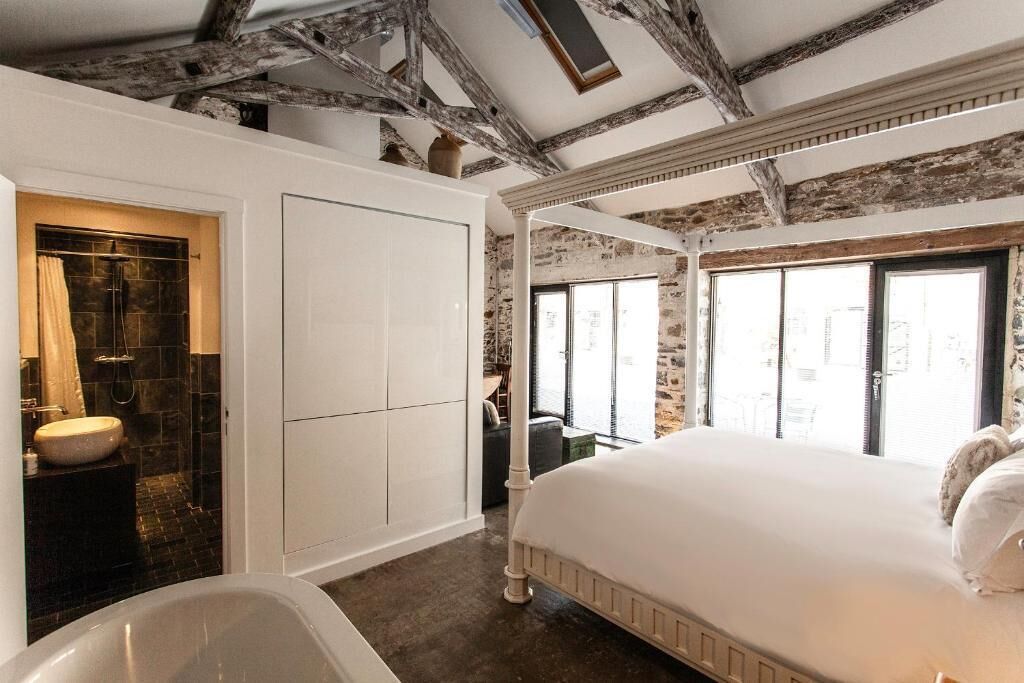A bedroom with a large bed, a bathtub, and a view of the city through large windows.