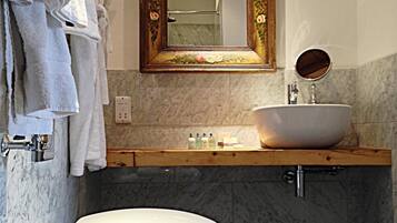 A bathroom with a white toilet, a wooden vanity with a white sink, and a mirror with a floral frame.