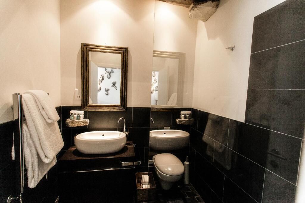 Un baño con dos lavamanos, un inodoro y un espejo con marco decorativo.