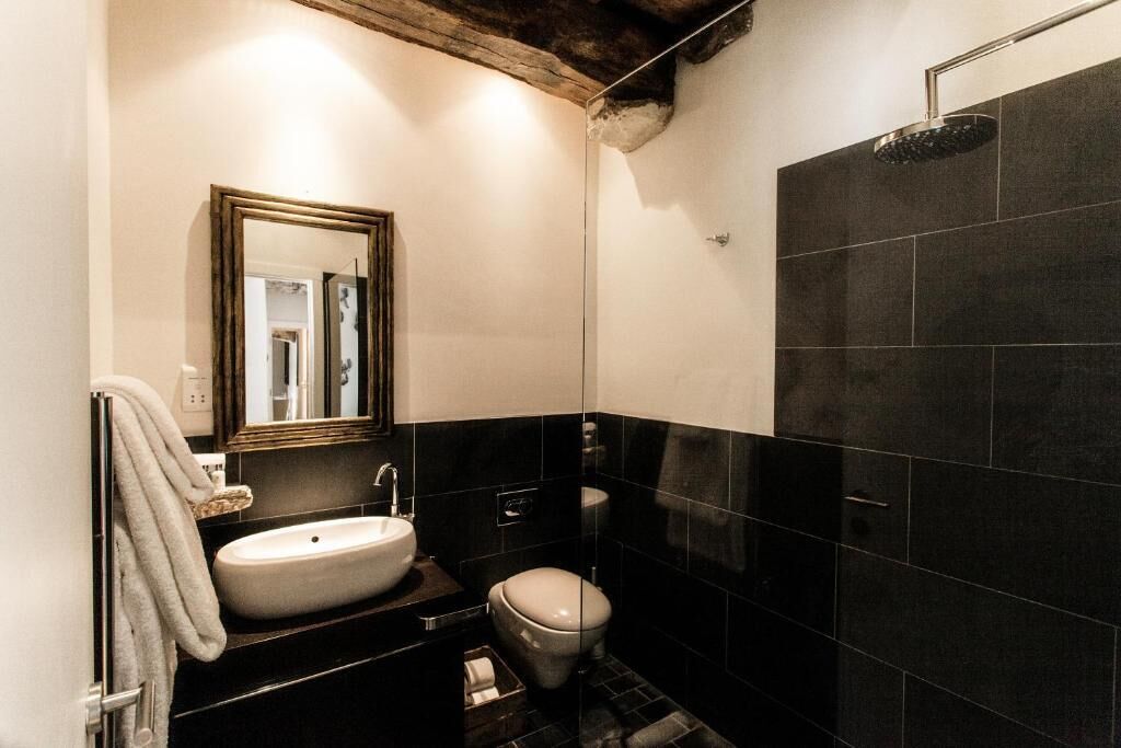 Een badkamer met een wit wastafelmeubel, toilet en douche.