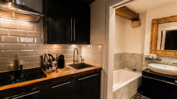 Una cocina moderna con estufa integrada, un lavamanos y armarios oscuros.