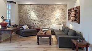 Ein Wohnzimmer mit einer Steinwand, zwei Sofas, einem Couchtisch und einem Holztisch.