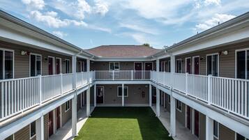Ein zweistöckiges Motel mit Innenhof, Balkonen und einer flachen Dachfläche.