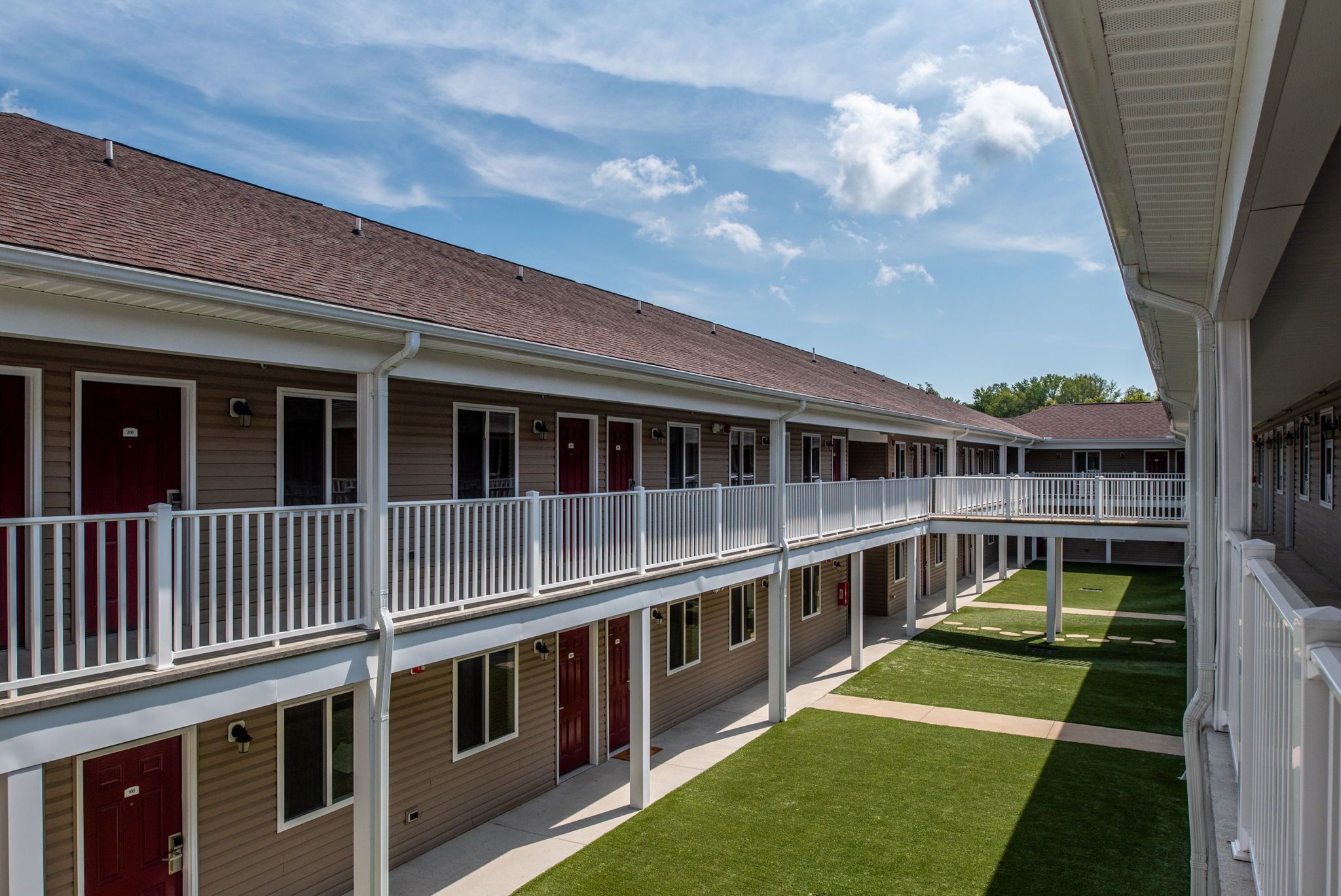 Un motel à plusieurs étages doté d’une cour intérieure, comprenant une galerie couverte et des chambres individuelles avec balcon.