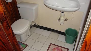 Un baño pequeño con inodoro, lavamanos y un cubo de basura verde.