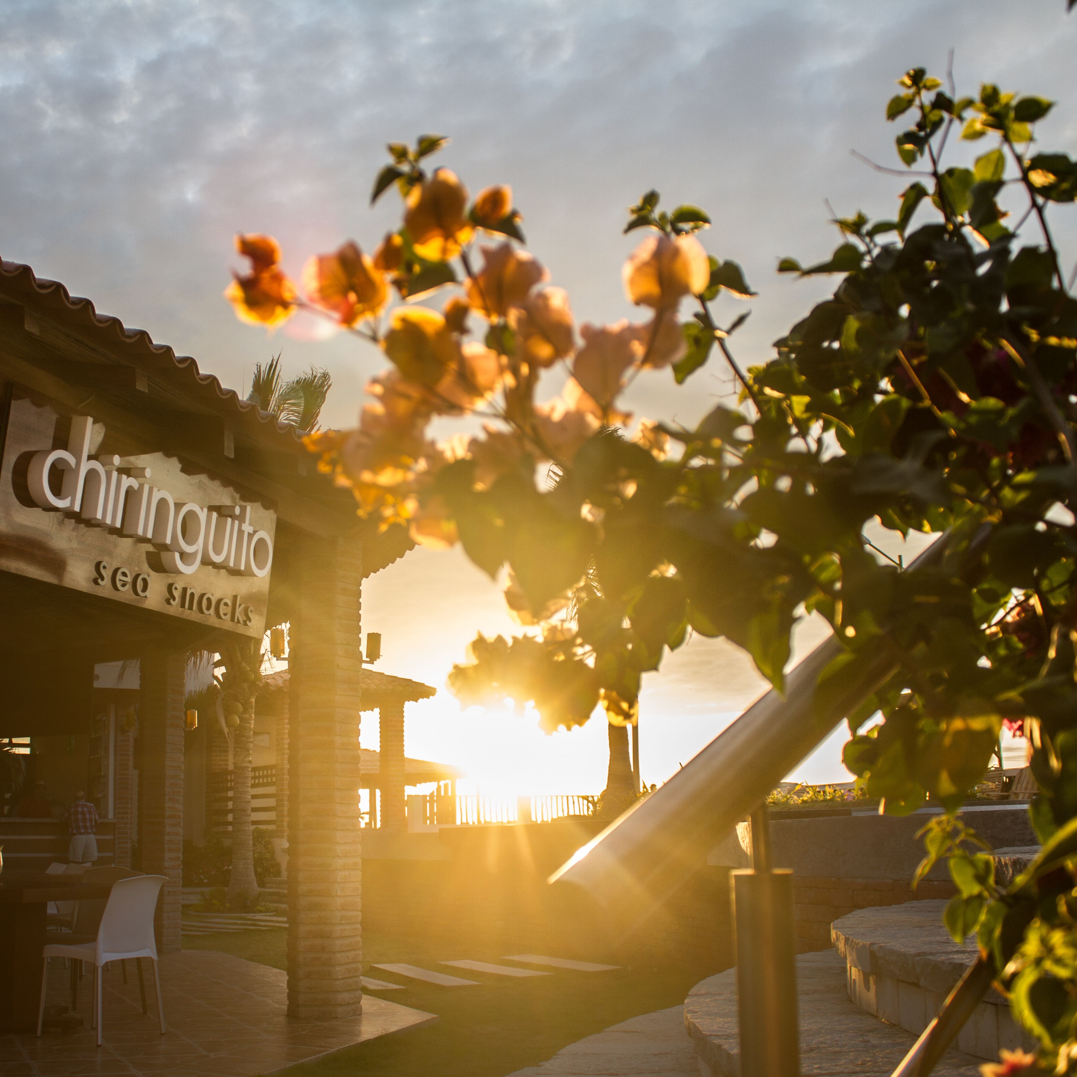 A building with a sign reading "Chiringuita sea snacks" and a patio area with chairs and tables.