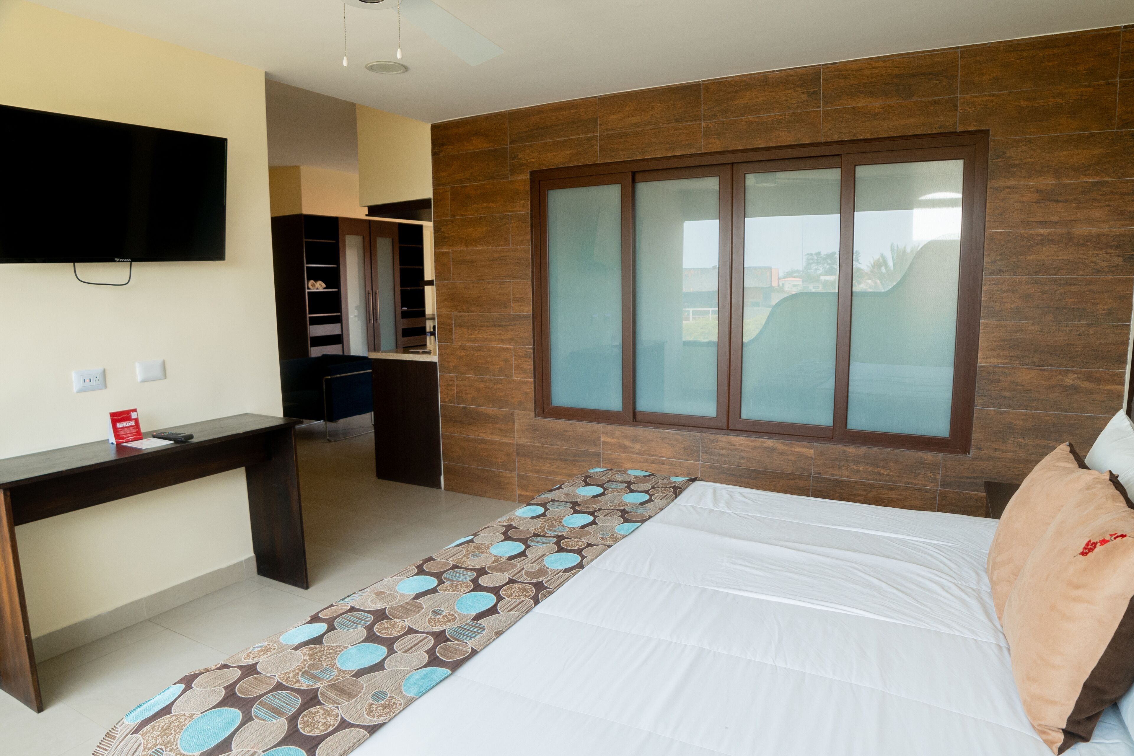 Un dormitorio con cama, escritorio, televisión y armario.