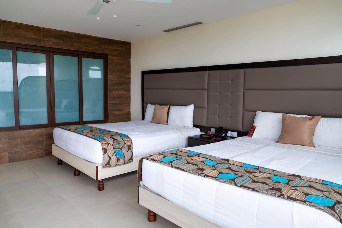 Habitación de hotel con dos camas, un ventanal grande y una pared decorativa de madera.