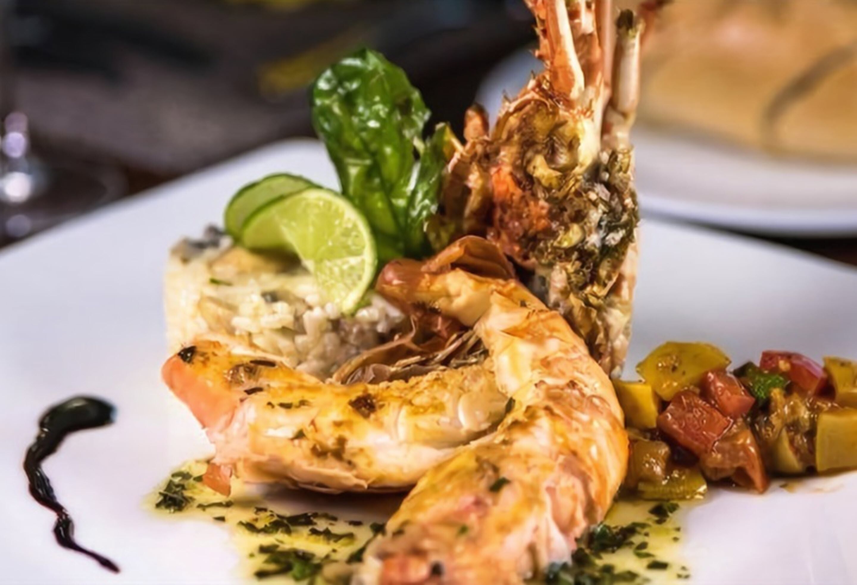 Un plato de camarones a la parrilla, un gajo de lima y una guarnición de verduras.