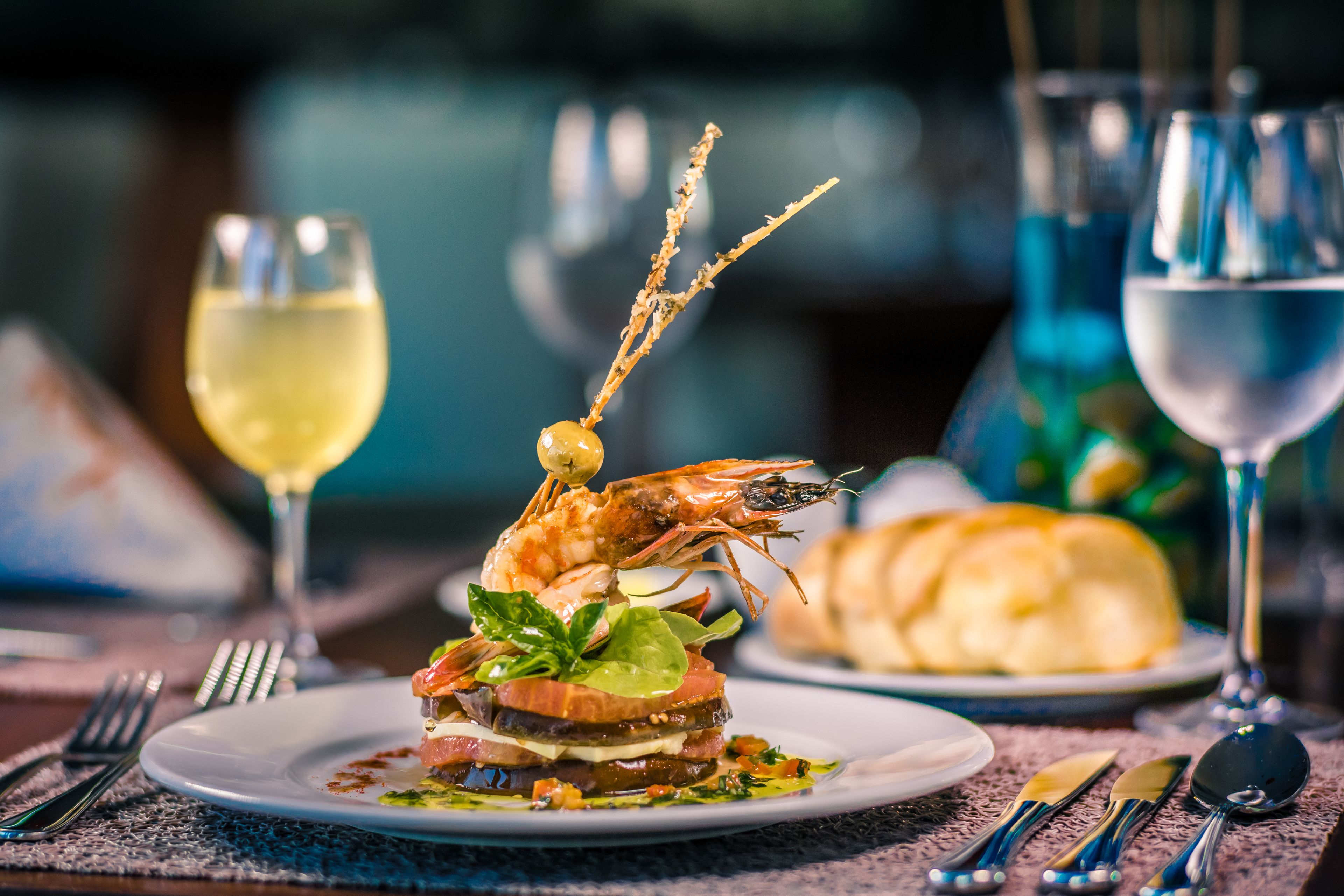 Plato de mariscos con un camarón encima, adornado con hierbas.