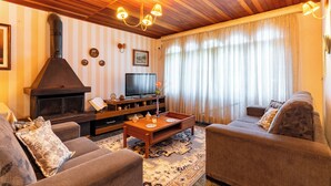 A cozy living room with a fireplace, comfortable sofas, a coffee table, and a television. - Pousada Recanto Sião (Campos do Jordão)